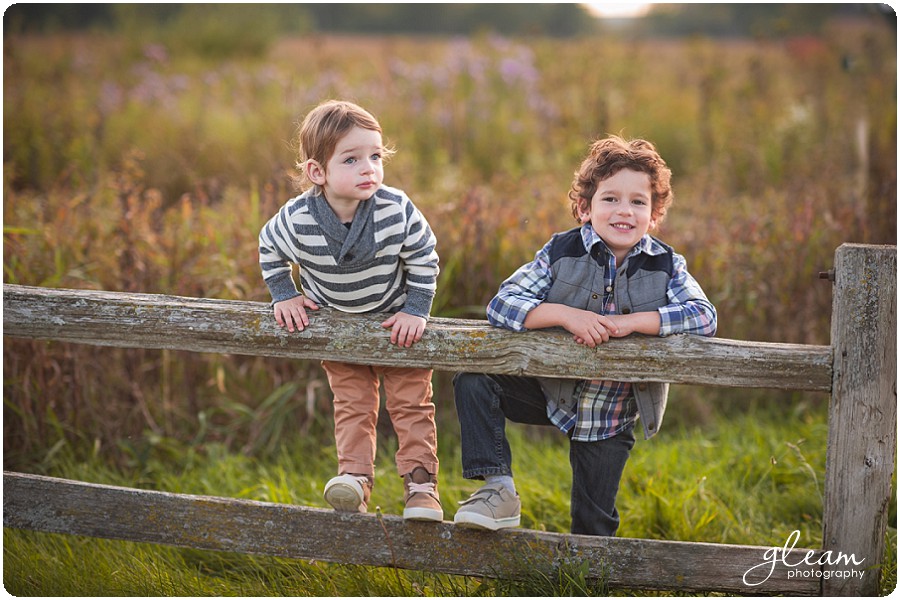 Portrait of two children climbing a rustic wooden fence